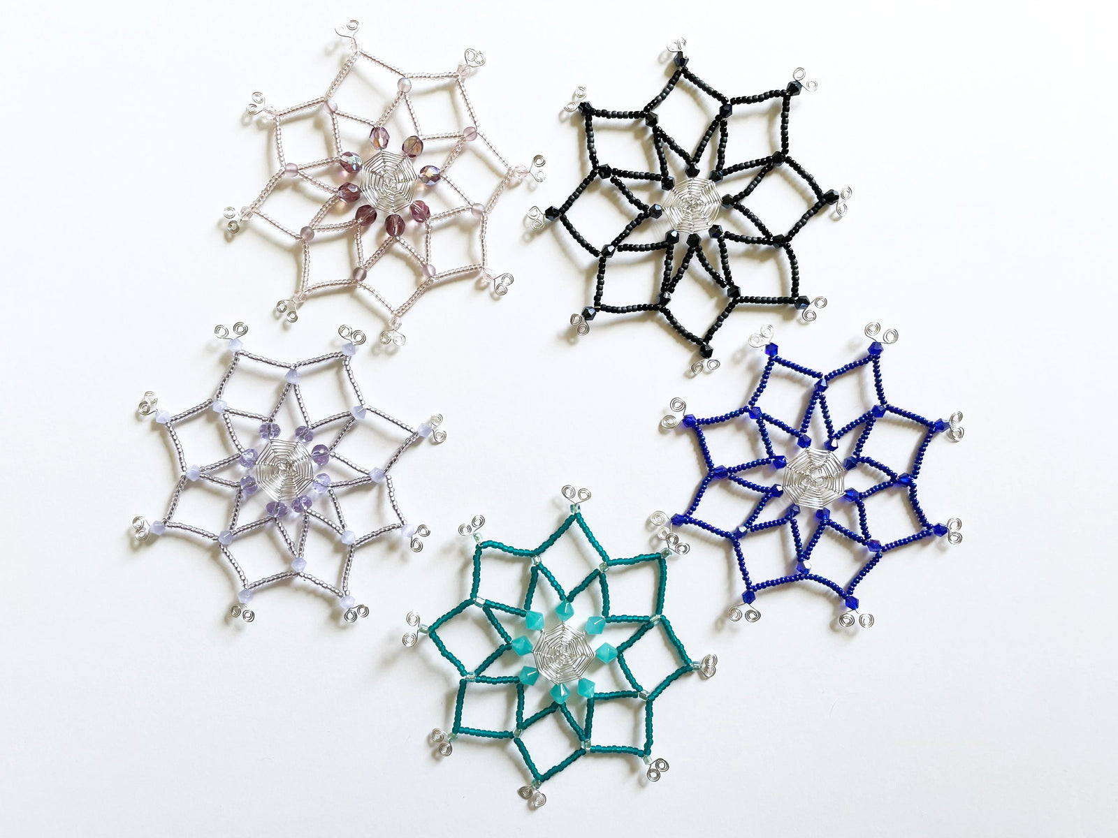 Christmas tree holiday ornaments, handmade wired snowflake ornaments, hand beaded designs with matte and shiny seed beads in lilac purple, navy blue, turquoise and pale pink.