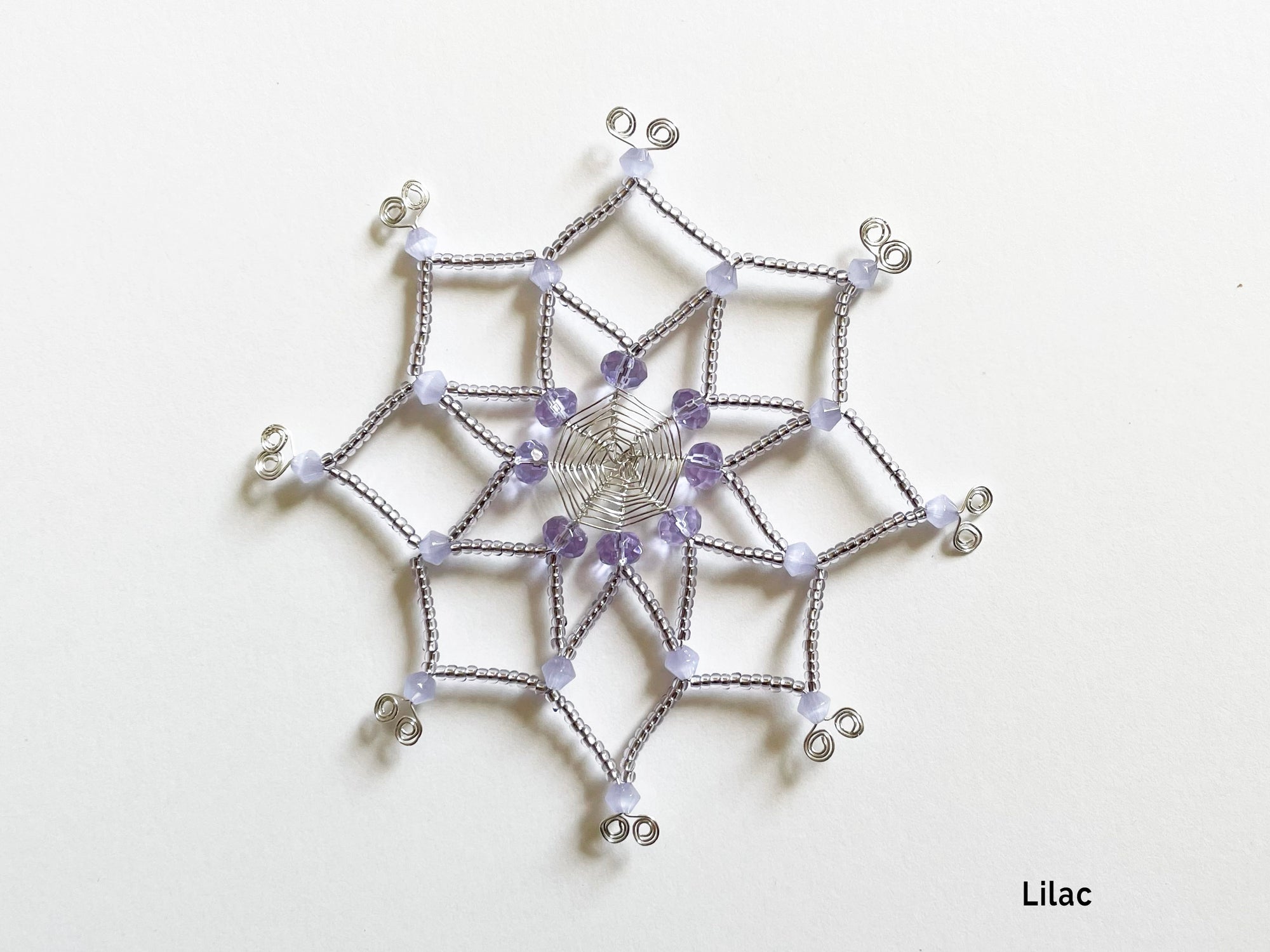 Beaded snowflake ornament, silver wire cut and bent by hand, delicately beaded with purple and lilac glass beads in unique design.