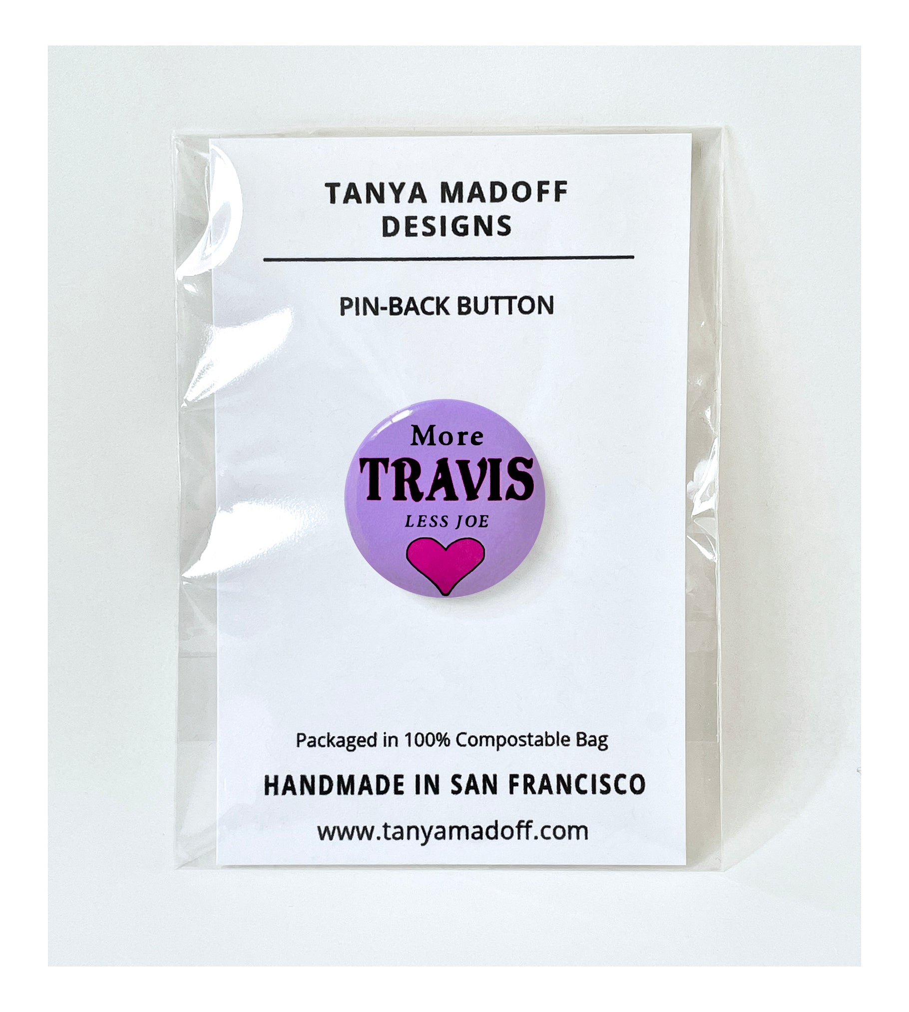 More Travis, Less Joe 1" Button, Taylor Swift and Travis Kelce inspired, with black lettering and magenta heart on purple background, packaged on recycled paper, in 100% compostable clear glassine bag