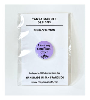 I love my significant other, 1 inch pin back badge, in black lettering and small branch with leaves on purple lilac background, shown packaged on  recycled paper card in 100% compostable clear bag.